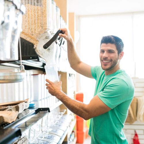 Portrait of smiling man serving food in container while buying in bulk at supermarket